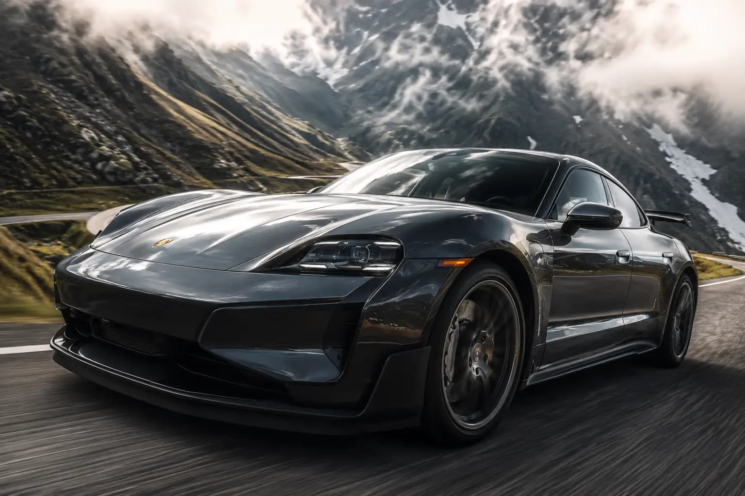 Dark grey Porsche Taycan Turbo GT cornering on a mountain road under low cloud
